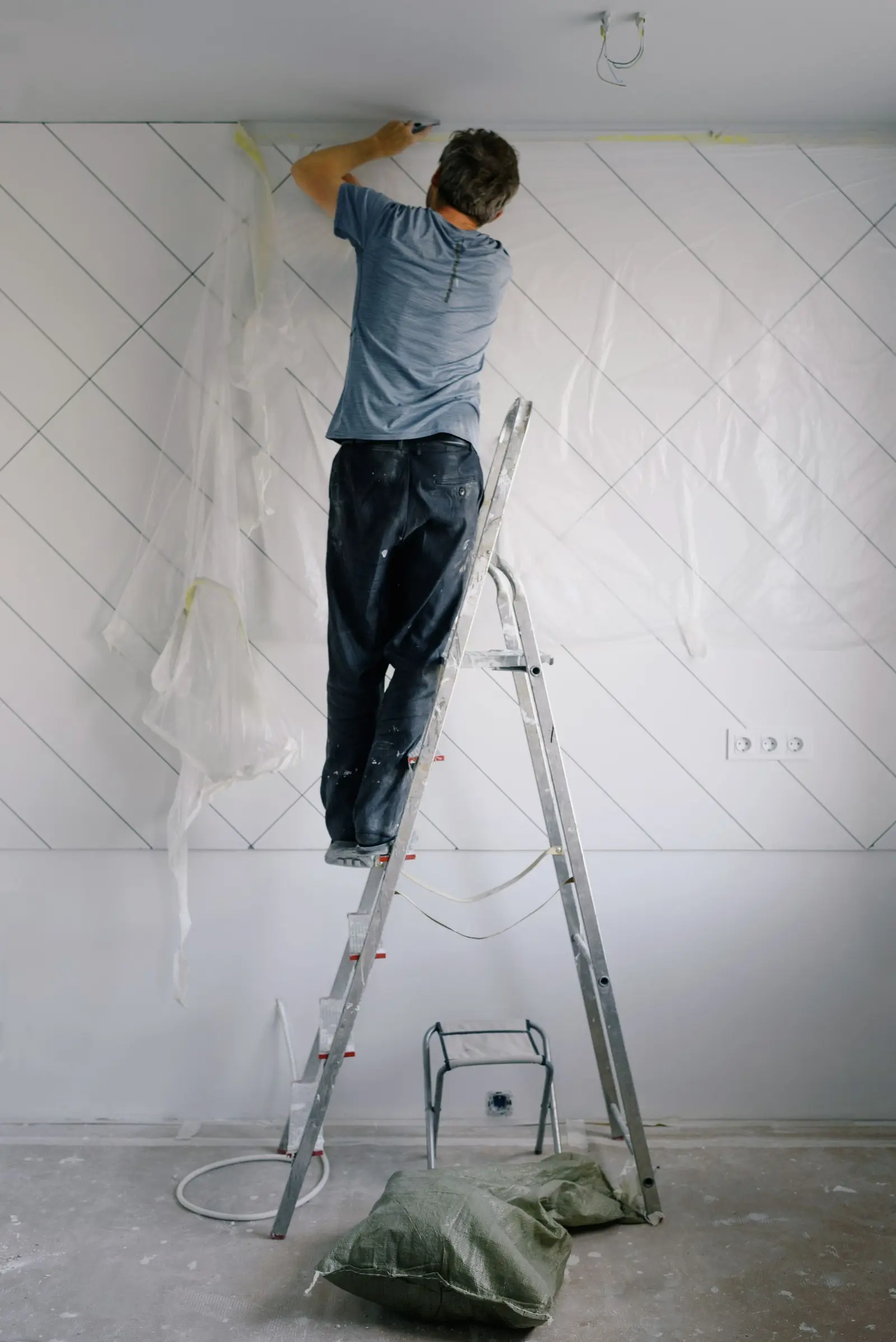 Peintre en bâtiment sur un escabeau dans une pièce protégée